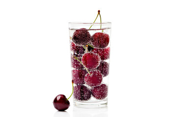 Cherries in a transparent glass with sparkling water isolated on white background