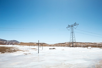power pylon in wild field with snow