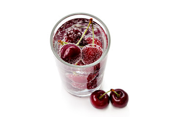 Cherries in a transparent glass with sparkling water isolated on white background. View from above