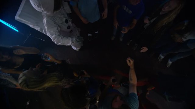 High angle view party crowd dancing in the club & funny astronaut flirting