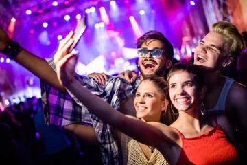 Happy friends taking selfie at music festival