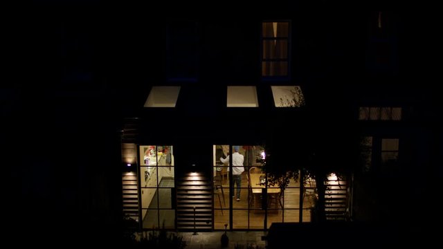 Man Locking Up His City Home And Turning Off The Lights At Night, View From Outside Looking In.