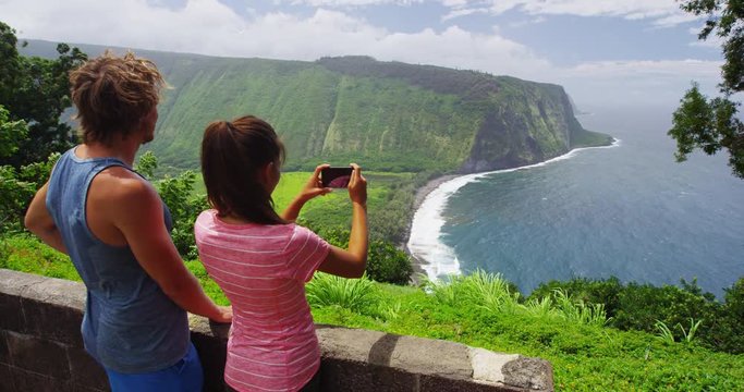 Tourists on hawaii taking photo using phone at Waipio Valley Lookout Big Island, Hawaii nature landscape. Couple on travel by Hawaiian nature at famous tourist destination. RED EPIC SLOW MOTION.