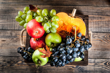 Autumn and thanksgiving harvest concept. Seasonal fall fruits and pumpkin on wooden table, copy space
