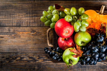 Autumn and thanksgiving harvest concept. Seasonal fall fruits and pumpkin on wooden table, copy space