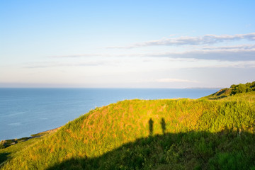 Fototapeta na wymiar Shadow of two photographers on hill next to sea