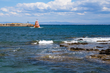harbor head at the sea with red and white striped beacon