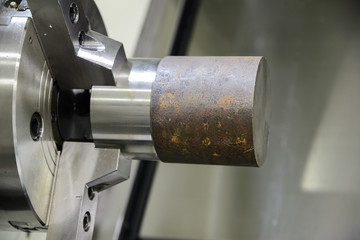 Fototapeta na wymiar Close up of the CNC lathe jaw clamping raw material steel rod .Hi-precision CNC machining concept.Raw material steel rod for CNC lathe precess