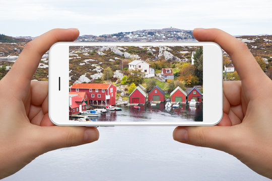 Woman take photo of scandinavian village by phone.