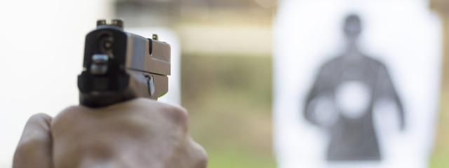 Man Firing Pistol at Target in Shooting Range - 172818507