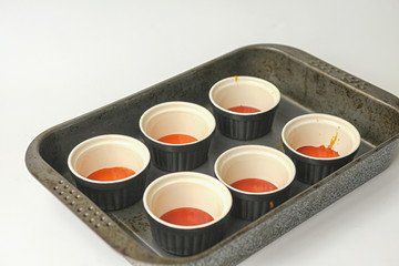 Six pots with caramel in oven tray