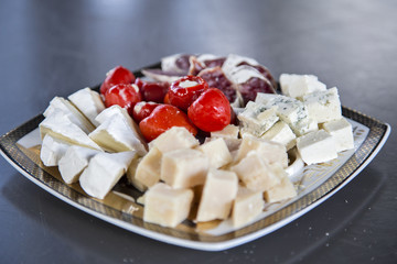 Assorti of cheese lying on the dish with peppers.horizontally.