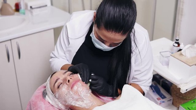 Professional comsetologist in mask making multiple injections in woman's cheek during mesotherapy. Biorevitalization and face lifting, non-surgical medicine treatment