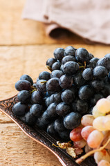 Two type of fresh ripe grapes blue and green on a vintage old tray. Close up.