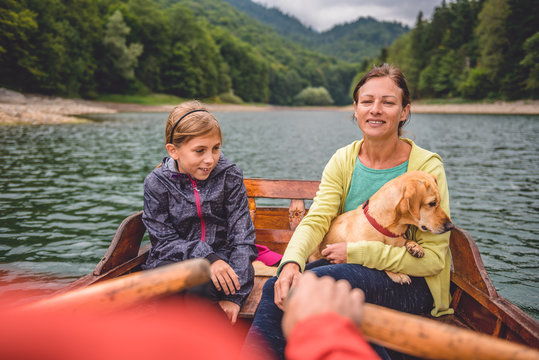 Family with dog rowing on a mountain lake