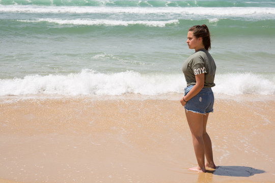 Portrait of young girl in a green top and denim jeans on a beach background