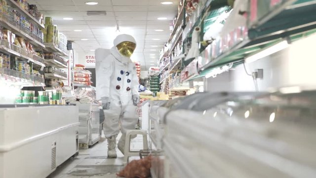  Man dressed as an astronaut shopping for groceries at night - EDITORIAL