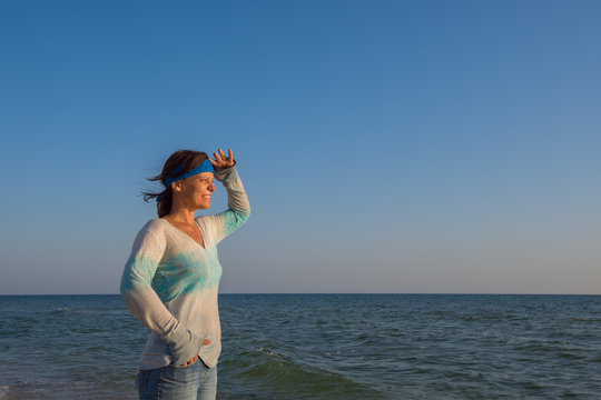 Happy female traveler stands alone on the sea coast