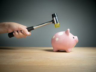 Piggy bank, savings, investments ,currency concept : A hand holding a hammer which is raised above...