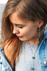 Fashionable girl in a jeans jacket on a white background. Stylish blonde in jeans.