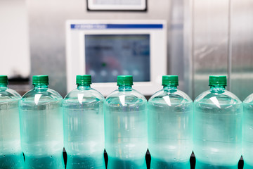 Bottling plant - Water bottling line for processing and bottling carbonated water into green bottles. Selective focus. 