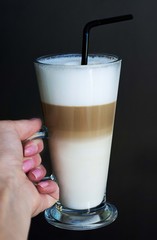 Latte in hand on black background