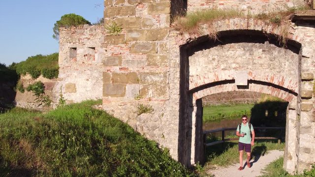Young handsome male photographer walking in ancient ruins with his compact camera