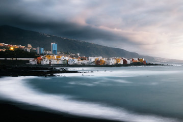 View of colorful houses of Puerto de la cruz, Jardin beach with black sand and Atlantic ocean, Tenerife, Canary islands, Spain. Long exposure