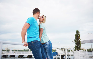 Fototapeta na wymiar Beautiful young couple kissing on a pier near water