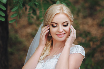 Naklejka premium The beautiful bride blond in a wedding dress for a walk on the nature. Summer wedding.