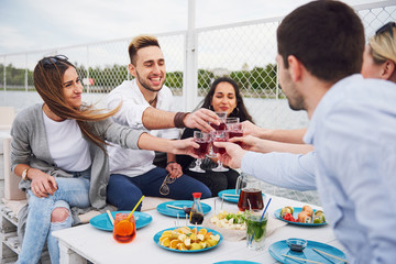 Happy young friends were sitting at a table and having a picnic outdoors