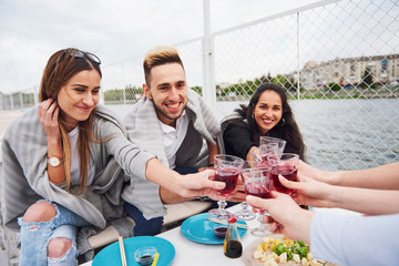 Happy young friends were sitting at a table and having a picnic outdoors