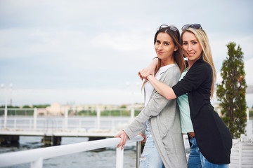 Fototapeta premium Happy young girl in stylish clothing brands on the pier near the water