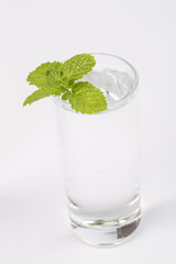Full glass of water with mint leaf isolated on white background.