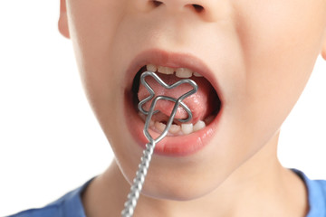 Cute boy with logopedic probe for speech correction on white background, closeup