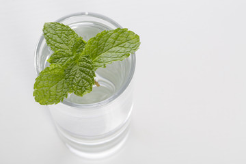 Full glass of water with mint leaf isolated on white background. Closeup.