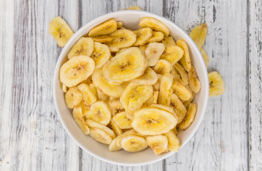 Dried Banana Chips on wooden background; selective focus