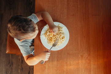 The child at the table eating macaroni and interesting angle