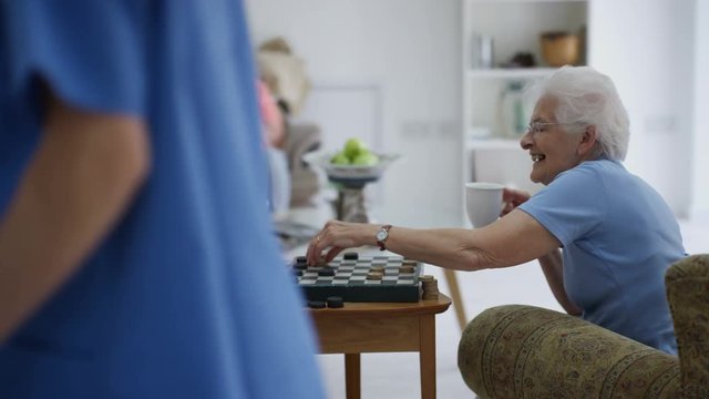 Cheerful senior ladies playing draughts in a nursing home.
