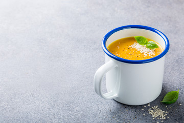 Delicious homemade carrot soup with meat sesame seeds in enamel mug. Healthy food concept with copy space.