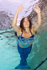 Model in a pool wearing a mermaid's tail.