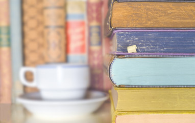 stack of books and a cup of coffee on a bookshelf, selective focus