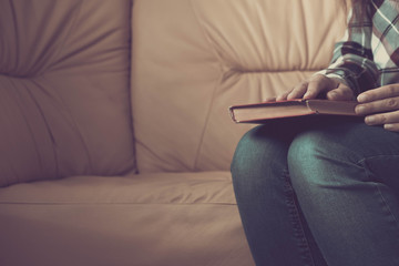 Young woman reading. Close up on woman hands turning page in vintage book. Woman read a book. Soft photo of female hands holding open book home interior background. Woman place her arms on her lap