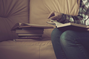 Young woman reading. Close up on woman hands turning page in vintage book. Woman read a book. Soft photo of female hands holding open book home interior background. Woman place her arms on her lap