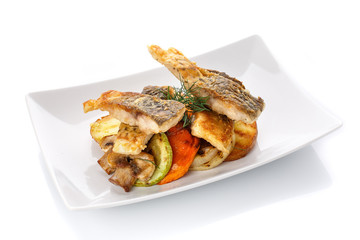 Fried fish with vegetables on a plate. Isolated on white