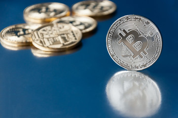 A few gold and silver   coins bitcoin lie on a blue backgroundConcept of crypto currency