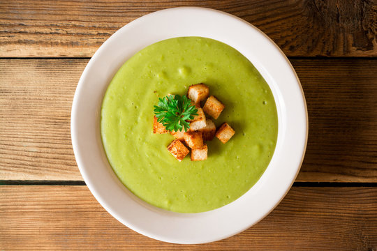Broccoli cream soup with croutons in plate on rustic wooden table