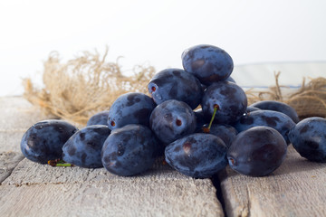 Plums. Blue and violet plums on wooden table.