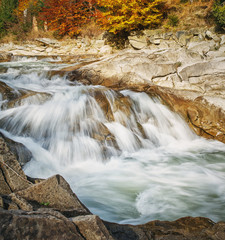 Landscape mountain river in autumn forest. View of the stony rapids.