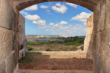 Coastal view on Balearic island of Minorca in the Mediterranean sea taken from an defensive old gun opening with the Town of Mahon across the estuary